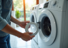 Fréquence idéale pour vider le filtre de la machine à laver : nos conseils pratiques Personne retirant un filtre de lave-linge moderne dans une buanderie lumineuse